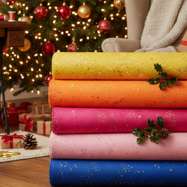 Stack of colorful fabric rolls in front of a decorated Christmas tree.